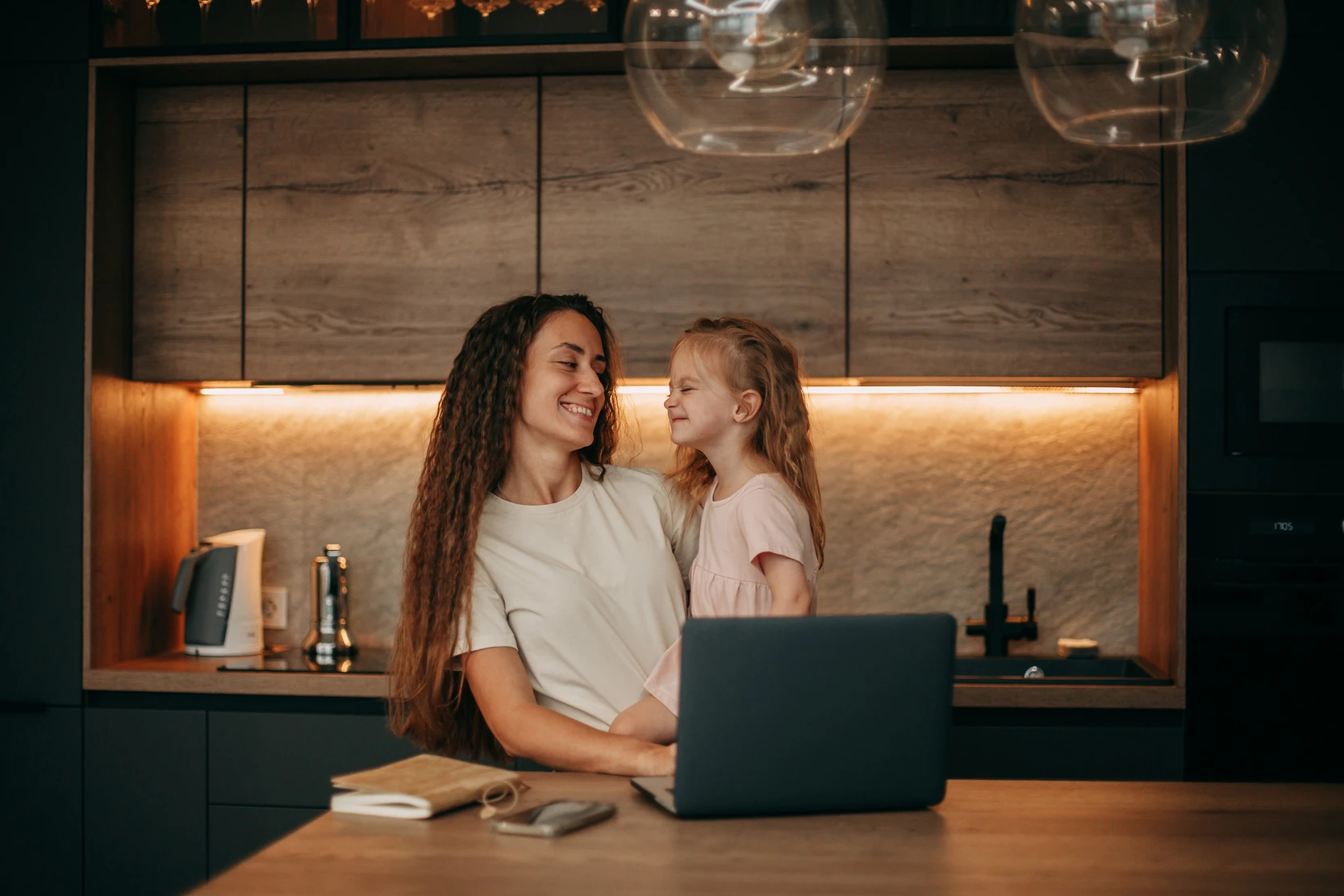 brunette-mom-with-long-wavy-hair-beige-t-shirt-home-kitchen-holds-daughter-with-blond-hair-pink-dress-her-arms-there-is-laptop-smartphone-notebook-table Primavolt Vorteile DSL